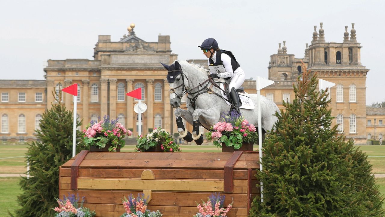 Laura Collett jumping a grey horse in front of Blenheim Palace