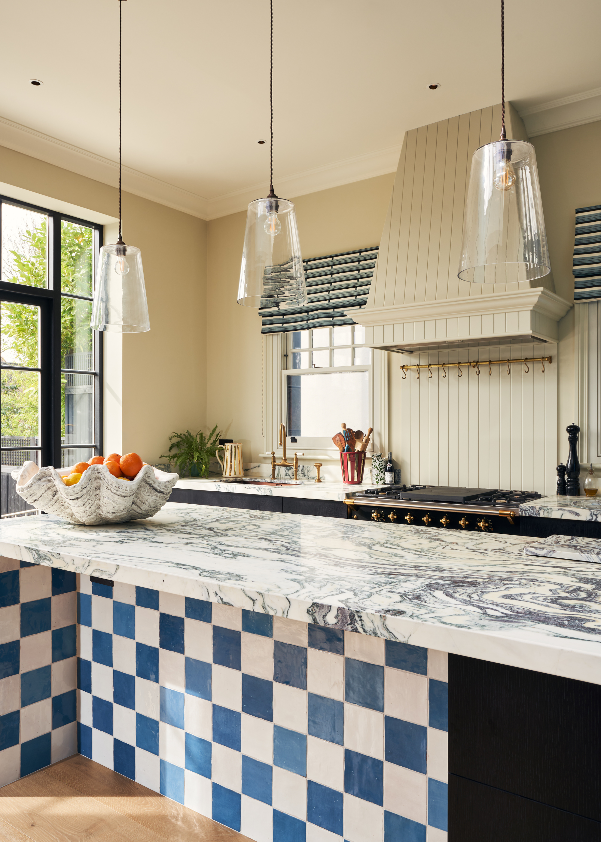 checkered blue and white kitchen island with marble counters and pendant lights