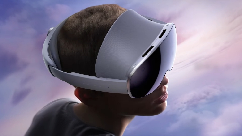A close-up profile view of a person wearing a sleek, grey mixed-reality headset against a soft, colorful background of clouds and sky.