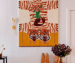 A living room wall with tiger wall art and wall sconce