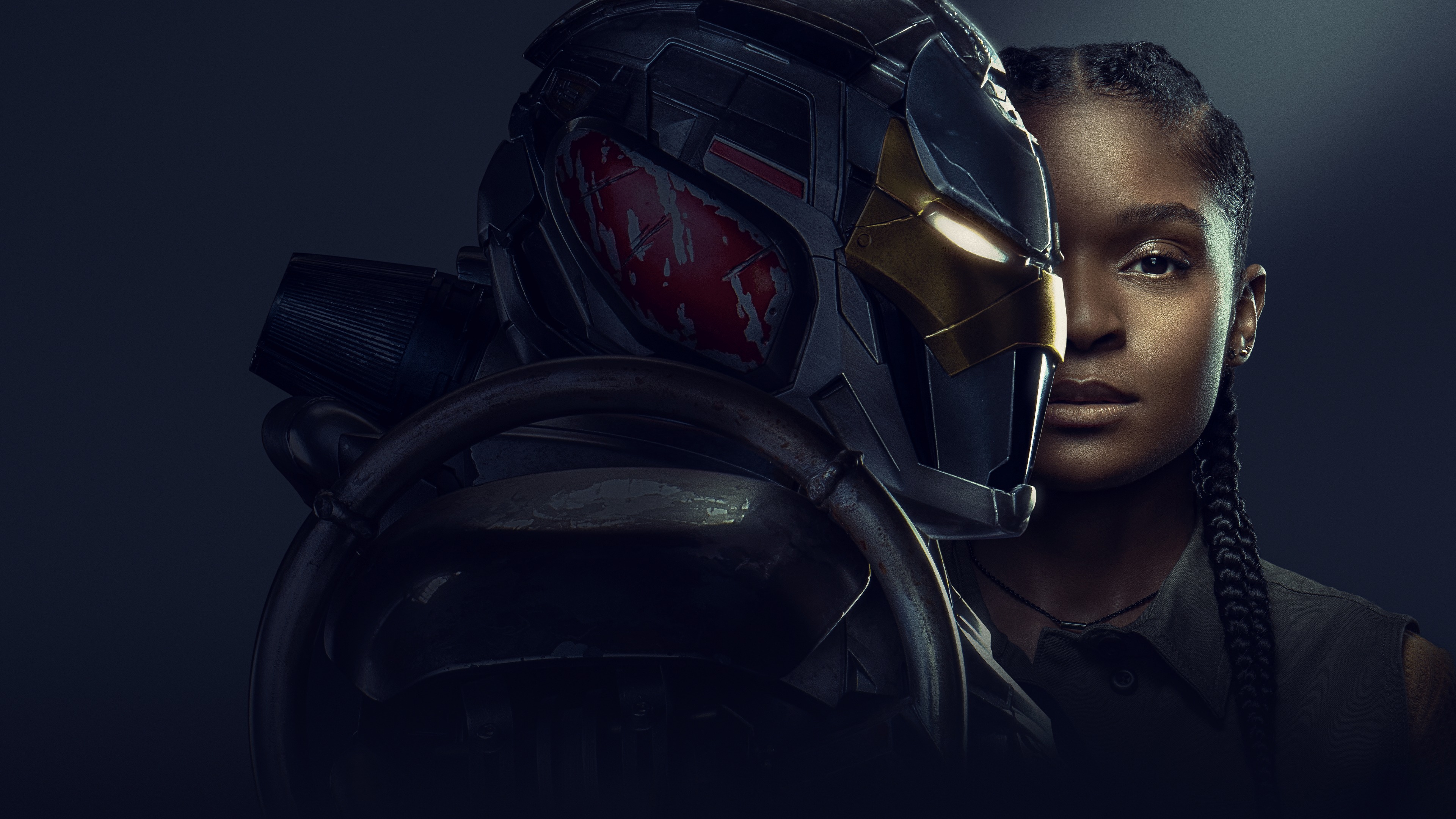 A robot looking person wearing a mask facing the side with half the face of a woman behind it