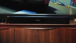the sonos arc soundbar on a wooden cabinet beneath a TV