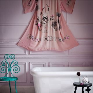 white bathroom with free standing tub teal chair and a pink kimono hanging on the wall