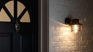 an industrial style light attached to a white brick wall, next to a front door