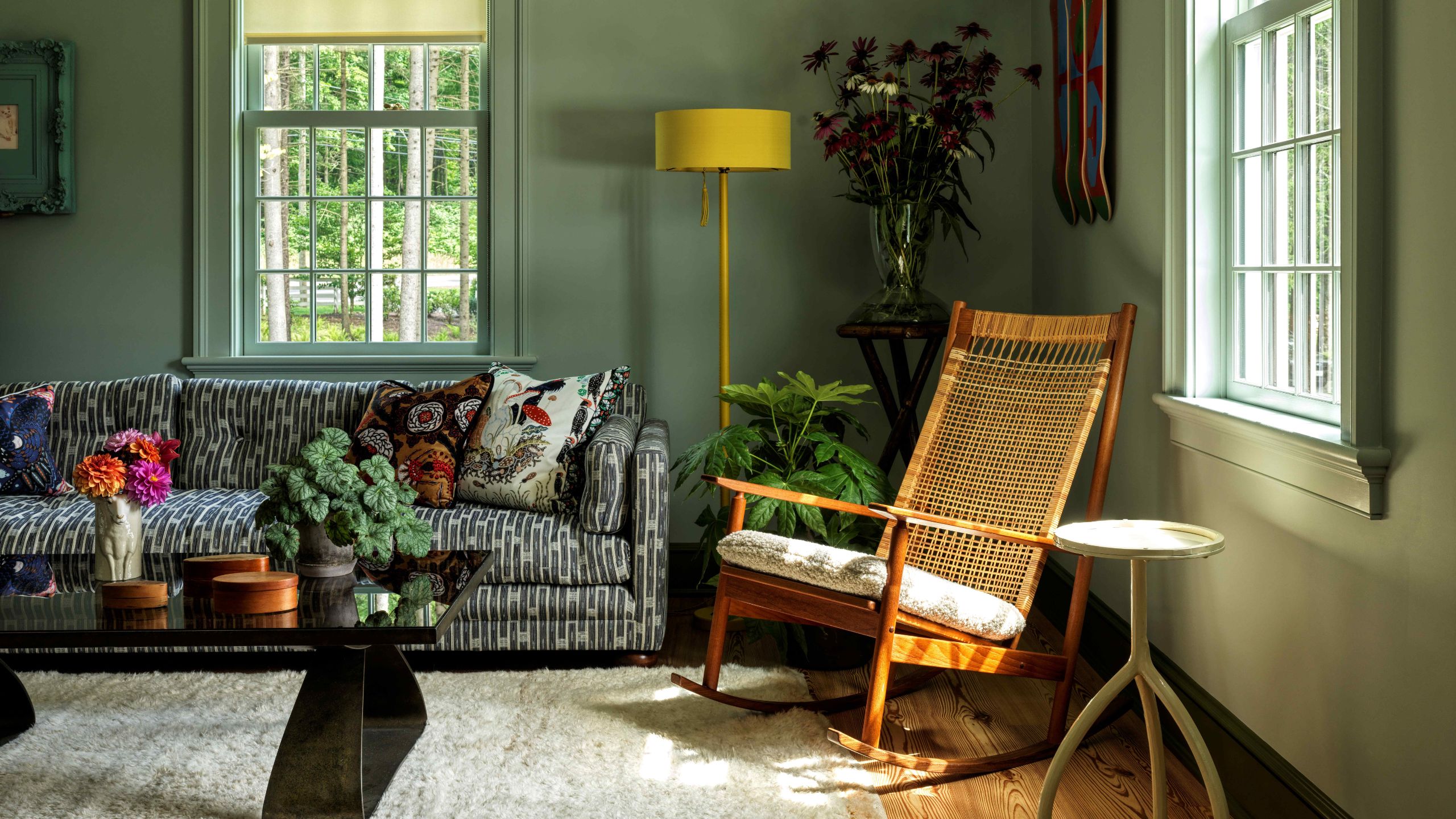 a hazy green painted living room with patterned sofa and rattan chair