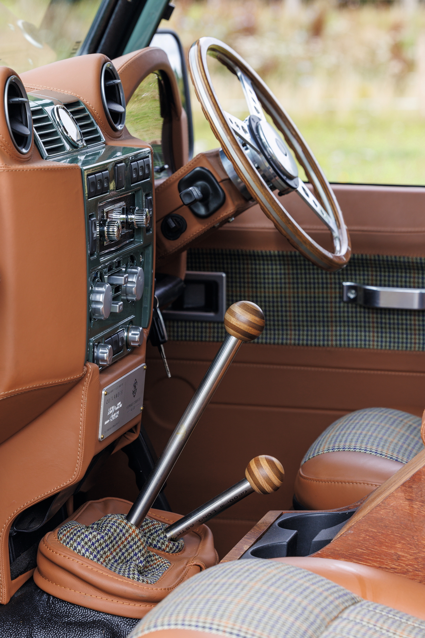 An interior shot of a Defender. There is tweed, brown leather and wood.