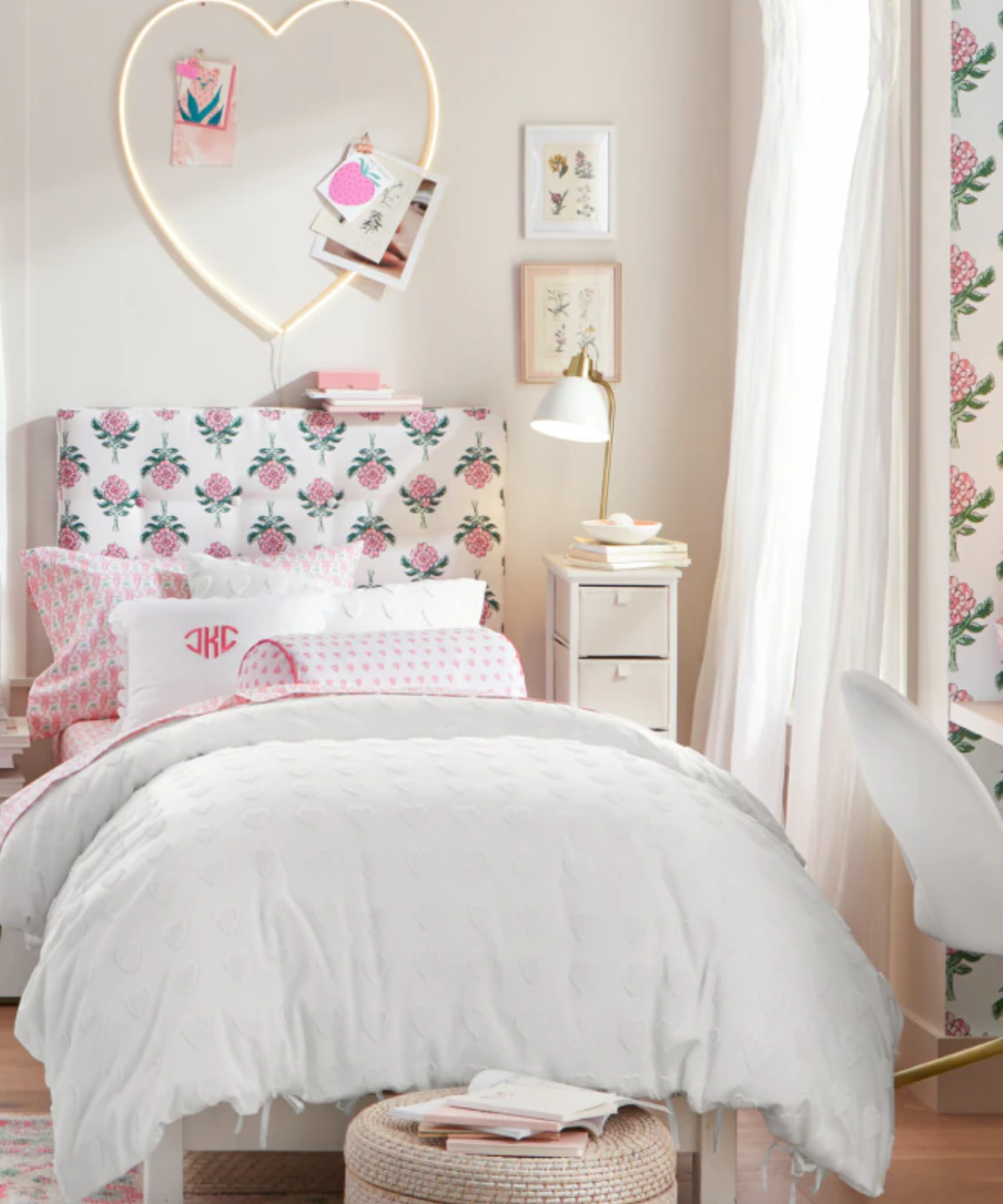 a bedroom with pink and white floral detailing and a twin bed with white bedding