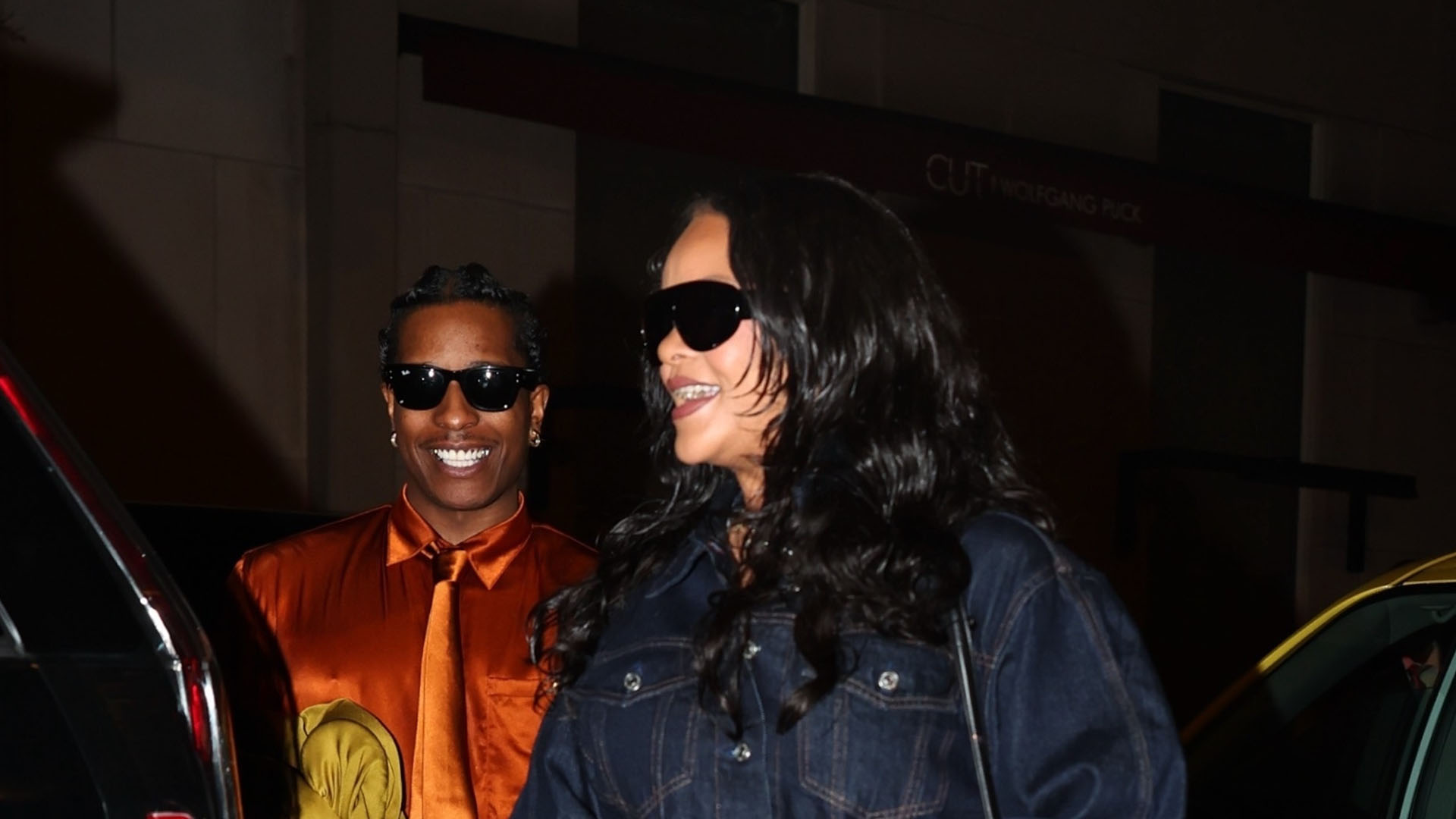 Rihanna wearing a dark denim cropped jacket, cropped denim jeans, and strappy heels