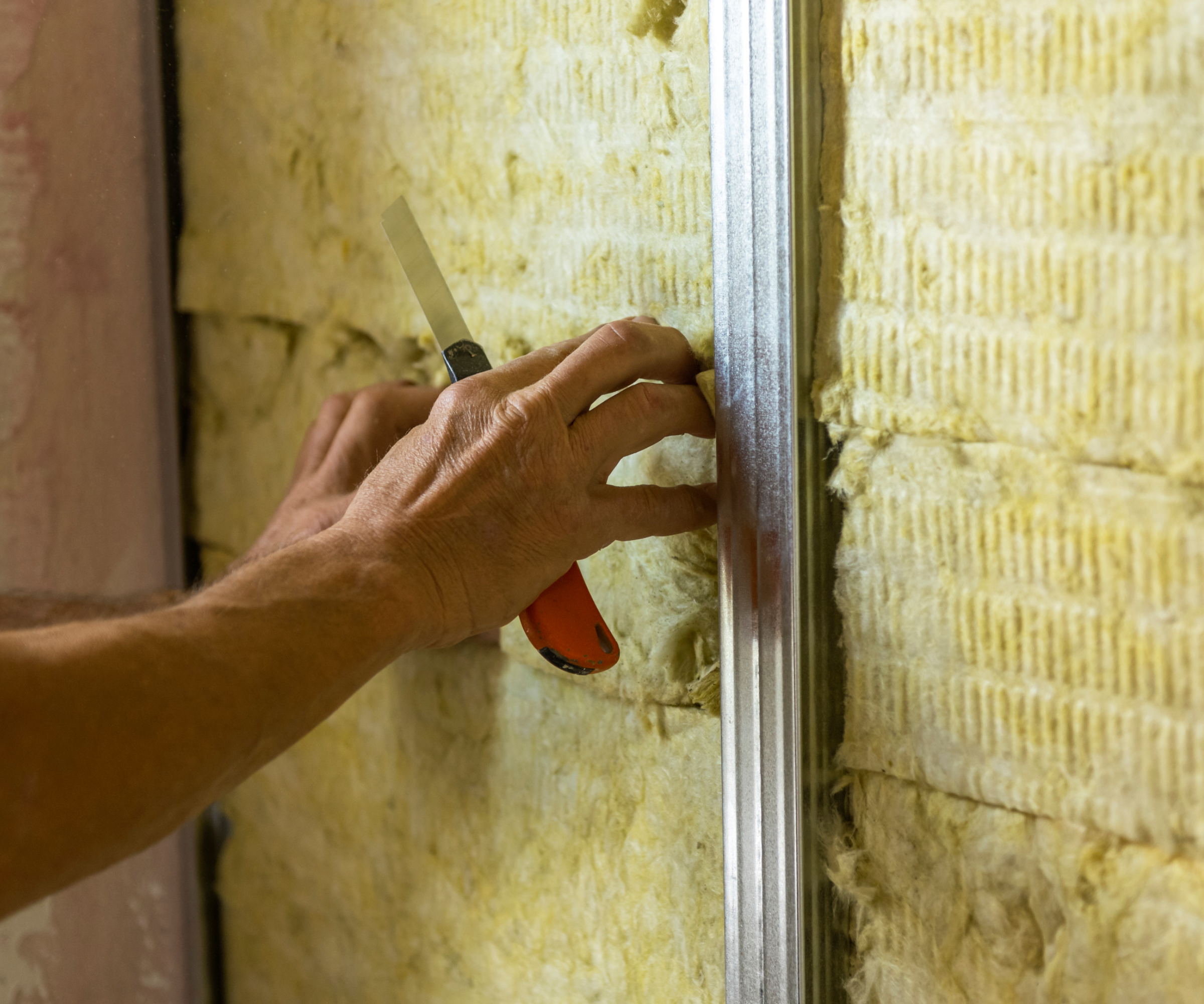 Person installing insulation on a wall