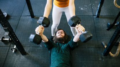 Concentrated man doing dumbbell workout. Well trained body with bulky  muscles. Sport equipment and weightlifting. Stock Photo