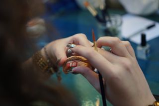 A woman making teeth jewels at a jewellery class in London