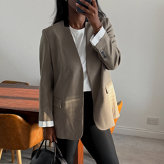 Woman wearing black leggings with white t-shirt, blazer, and black bag.