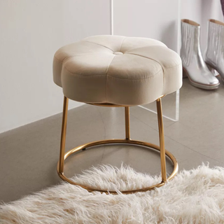 A velvet flower-shaped stool with gold legs, on a shaggy white carpet