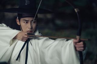 A man (Lee Jae-wook) in traditional Korean wear, aims a bow and arrow, in 'Dear Hongrang.'