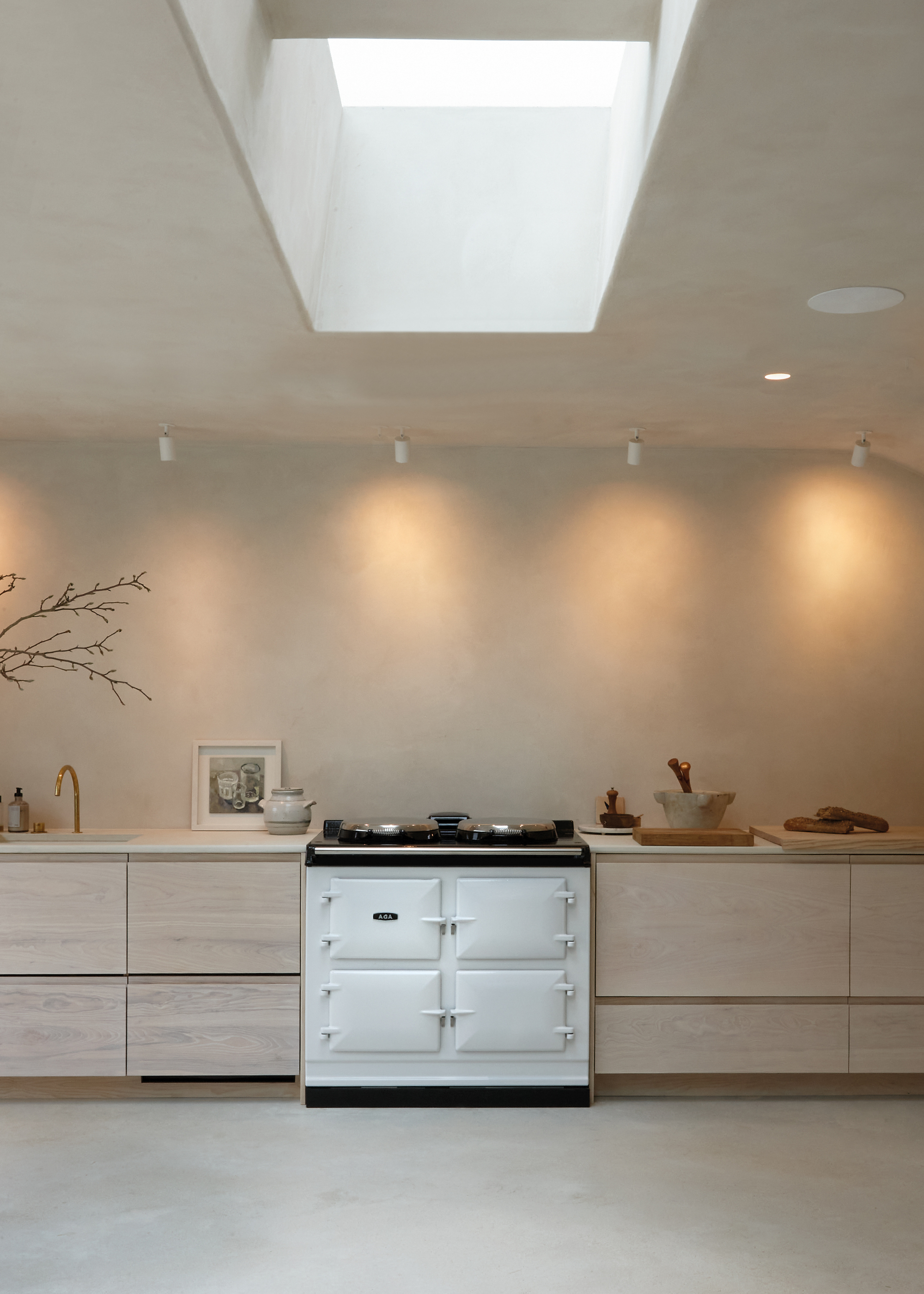 neutral modern aga kitchen with large skylight and a white aga in the middle