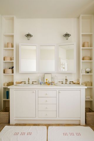 A bathroom with a double vanity and a triptych mirror