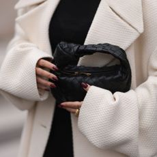 Woman holding black bag wearing burgundy nails