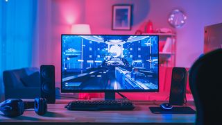 The best gaming monitors: a monitor sits on a desk surrounded by headphones and controllers