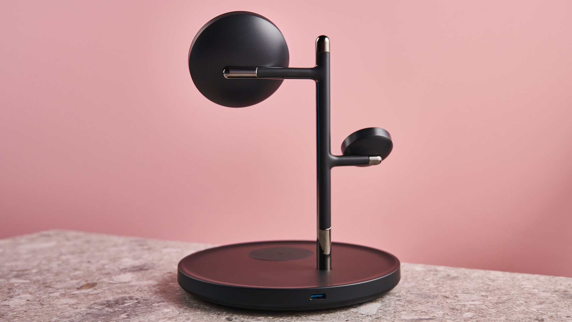 The back view of the Anker MagGo Charging Station 3-in-1 stand that is sitting on a stone-effect surface with a pink background.