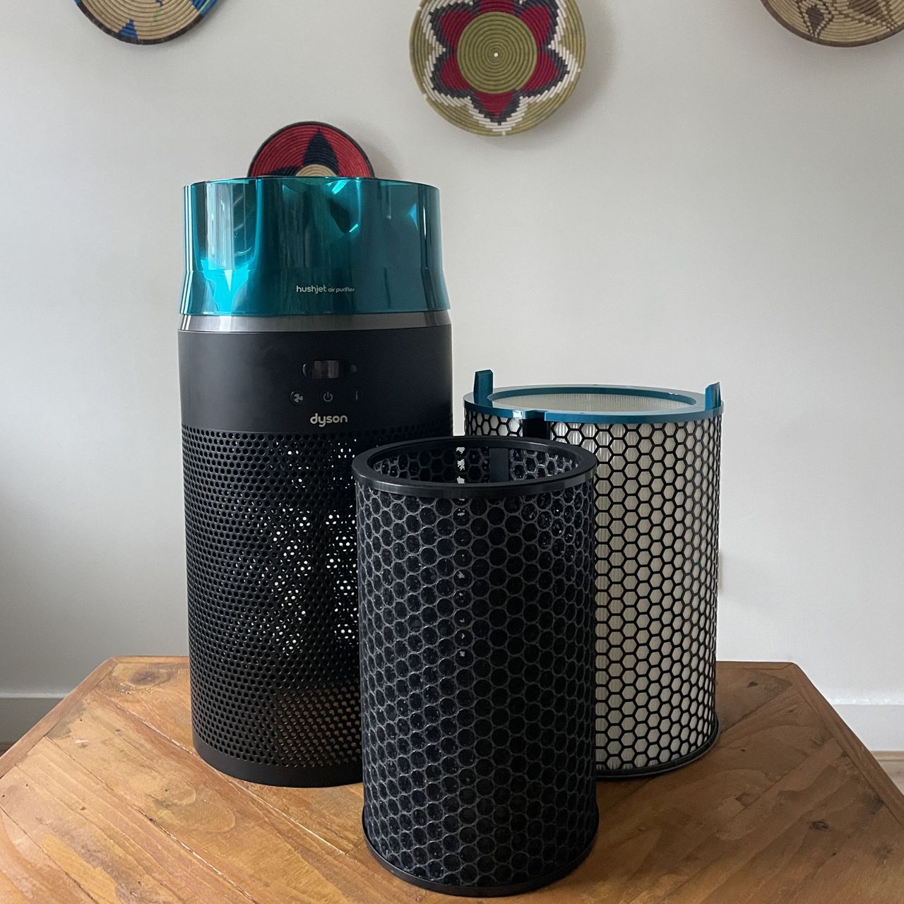 Dyson Hushjet Air Purifier with two filters sitting next to and in front of it on a wooden table