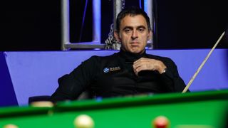 Ronnie O'Sullivan sitting looking at a pool table during the 2023 International Championship (Day 5) 