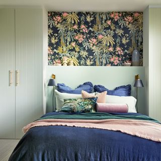 Green bedroom with bed in alcove and wallpaper above