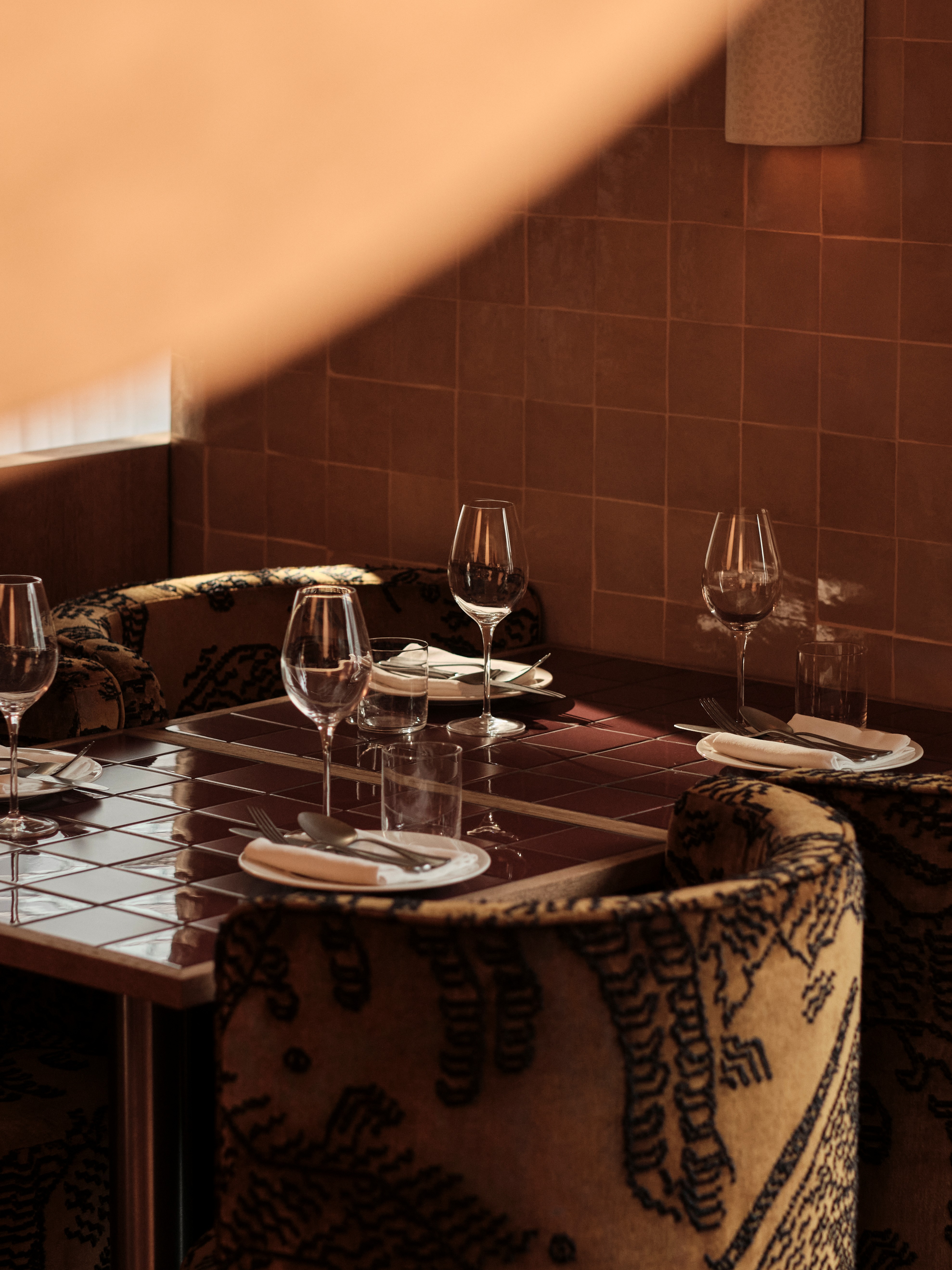 Interior shots of a restaurant with wooden surfaces, warm, sculptural lighting, lacquered and tiled surfaces, and a retro-inspired ambiance.