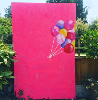 pink board with painted balloons in garden and plants