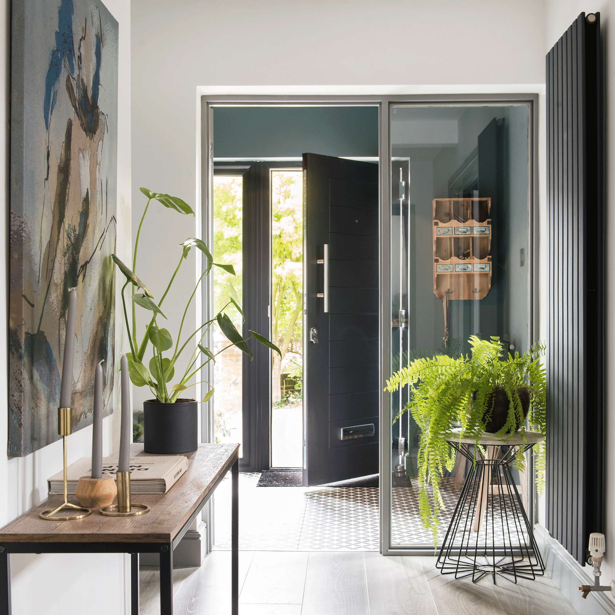 a contemporary hallway with an open front door a console table and a tall wall-hung radiator
