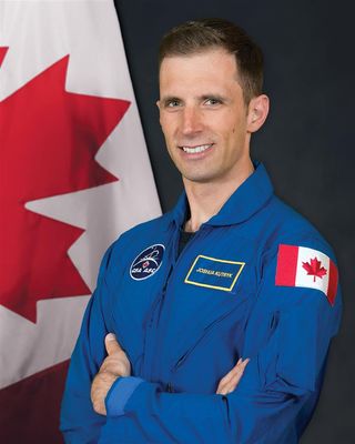 Canadian Space Agency astronaut Joshua Kutryk standing in front of a canadian flag with an astronaut suit on