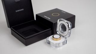 The gold Samsung Galaxy Ring with its box and charging case