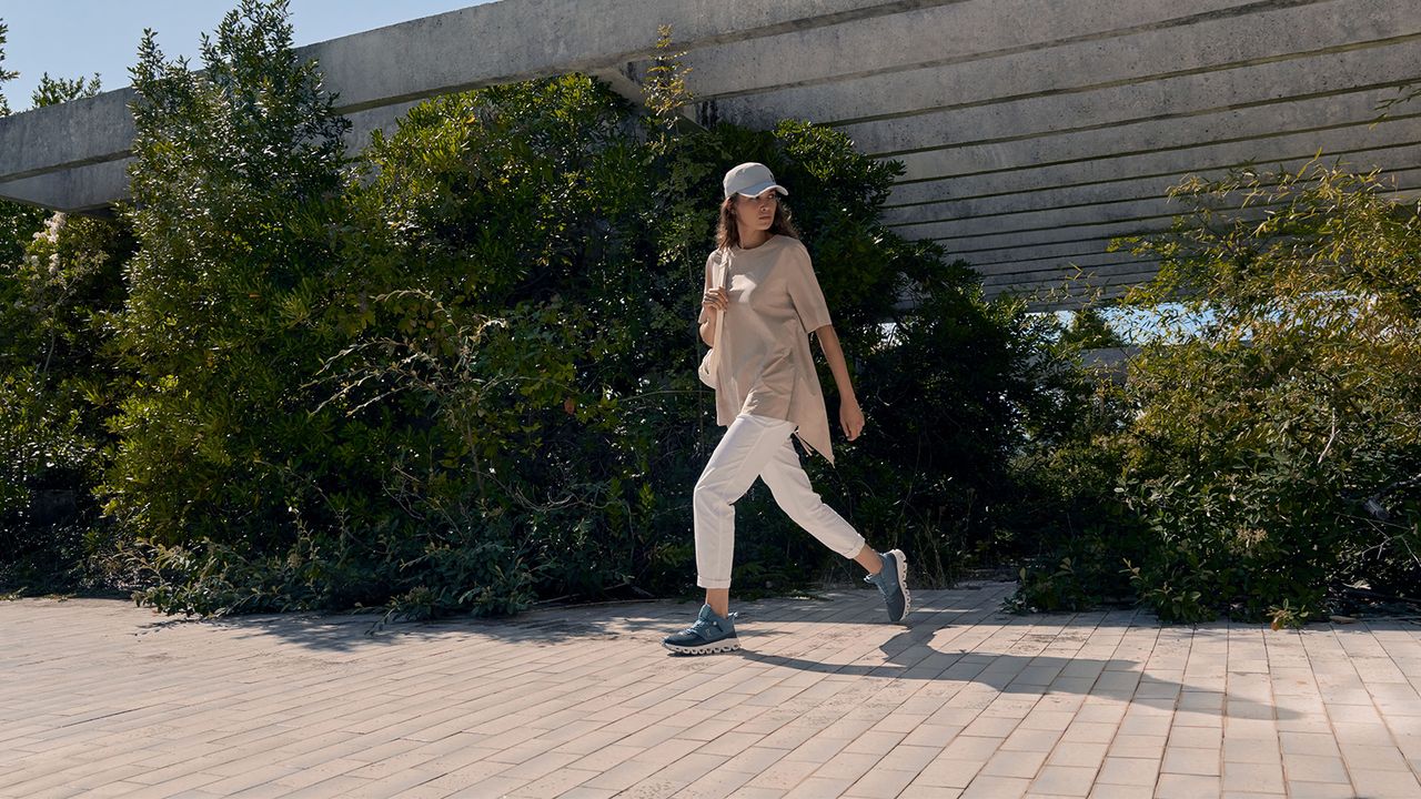 A woman out walking while wearing Navy colour On Cloud Hi walking shoes