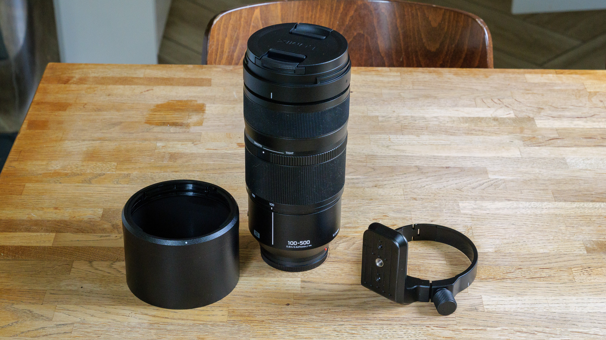 panasonic 100-500mm with lens hood and tripod mount on wooden table top