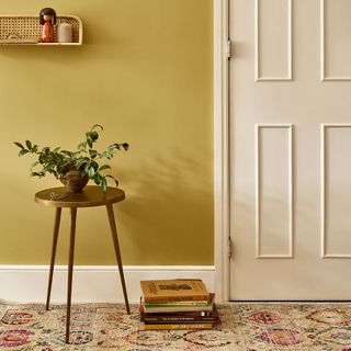 chrome yellow wall plant on table white door and stack of books