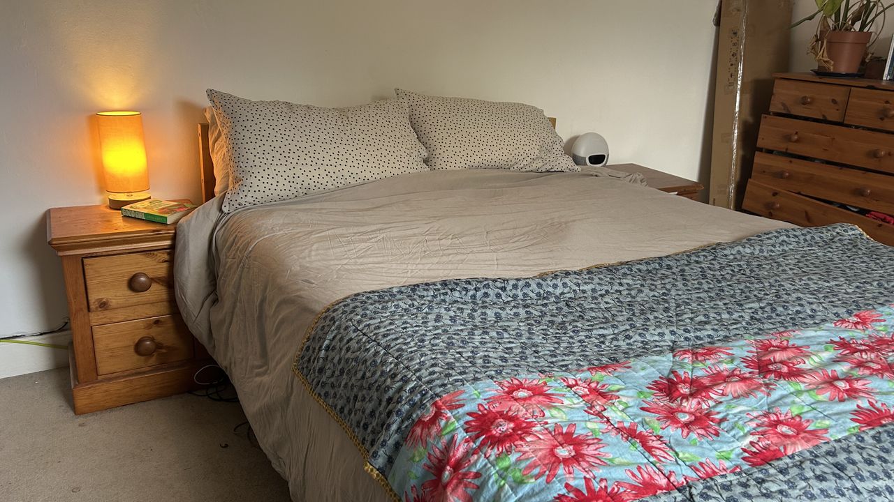 The Awara Classic mattress dressed in grey bedding with a lamp on a bedside table next to it