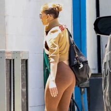 Jennifer Lopez wearing a tan jacket, brown leggings, and white sneakers