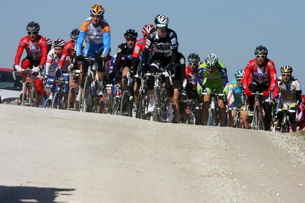 The peloton crests a rise on the white gravel roads.