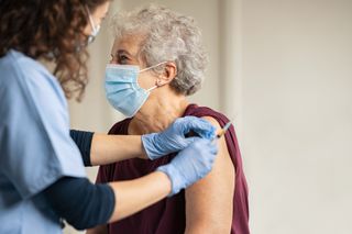 A healthcare provider vaccinating an older person.