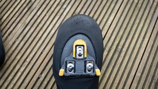 Le Col neoprene toe warmers fitted to white cycling shoes on wooden decking