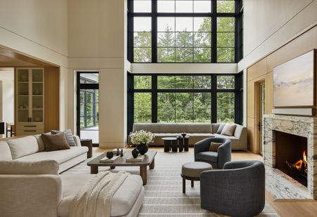 A large living room with double-height ceilings and neutral-toned furniture.