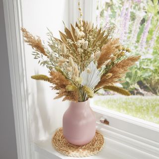 Bunch of dried flowers in ceramic vase on windowsill