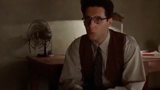 John Turturro as Barton Fink, wearing a suit and glasses.