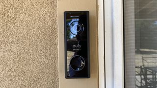 En svart Eufy Video Doorbell 2K sitter monterad bredvid en dörr.