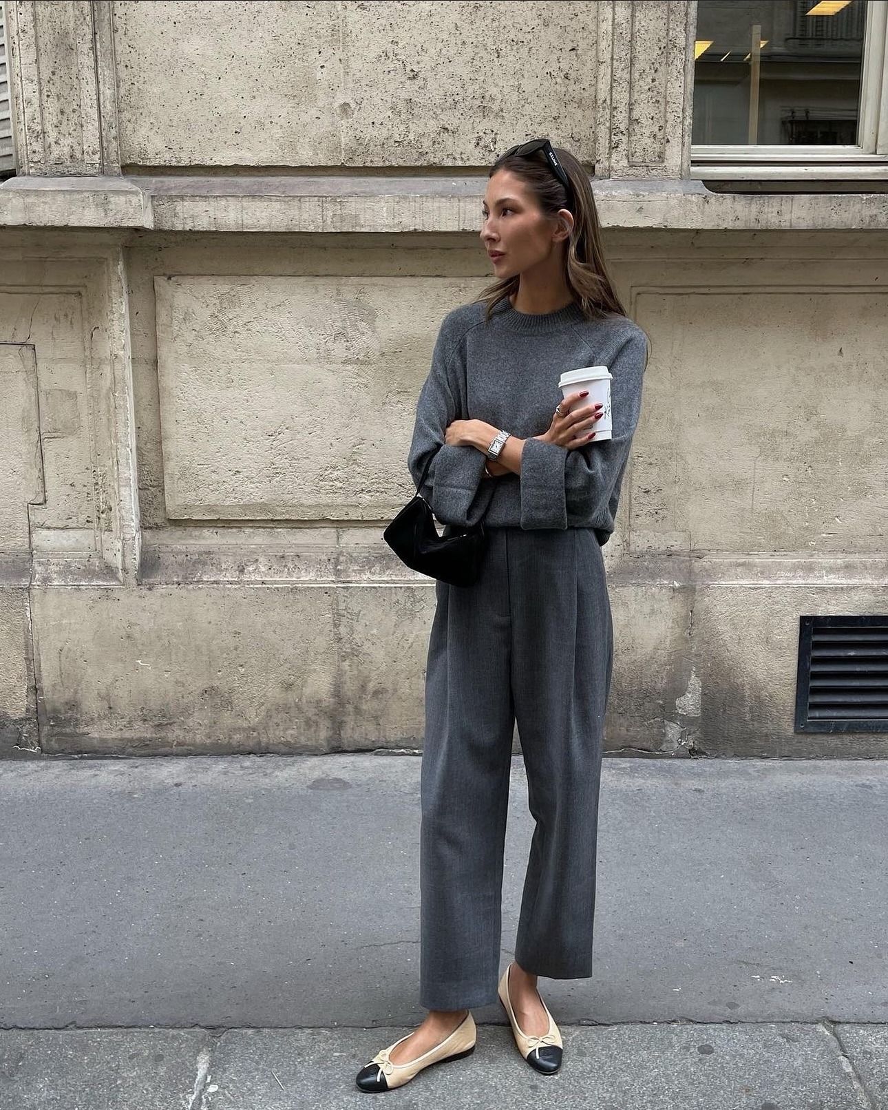 Influencer Felicia Akerstrom wears an all grey fit with a pair of pleated trousers and an oversized crewneck sweater.
