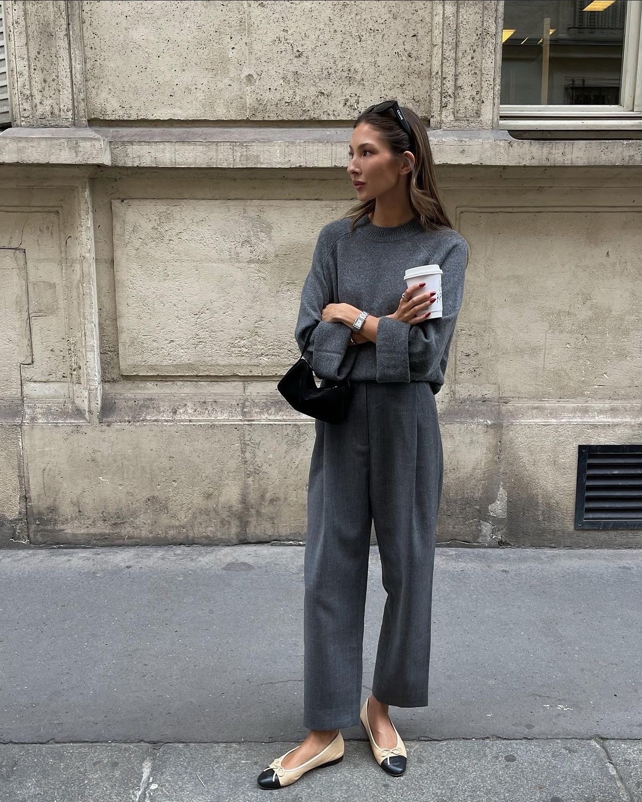 Influencer Felicia Akerstrom wears an all grey fit with a pair of pleated trousers and an oversized crewneck sweater.