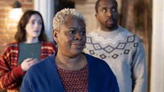Sutara Gayle in a blue cardigan as Betty stands in front of Charlotte Ritchie and Kiell Smith-Bynoe in festive knitwear as Alison and Mike in the Ghosts Christmas special.