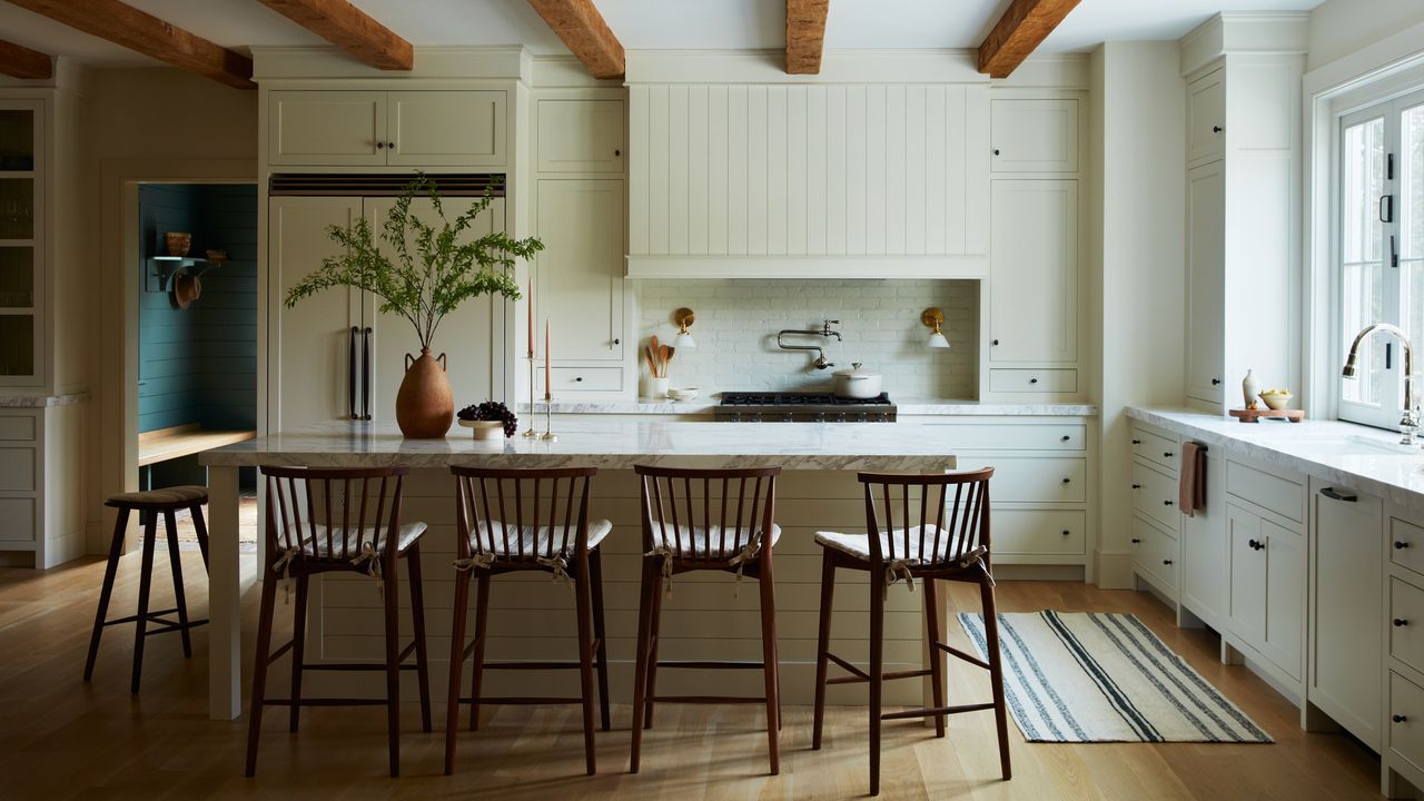 cream beamed kitchen with Shaker style cream cabinets, cream island and wooden bar stools 