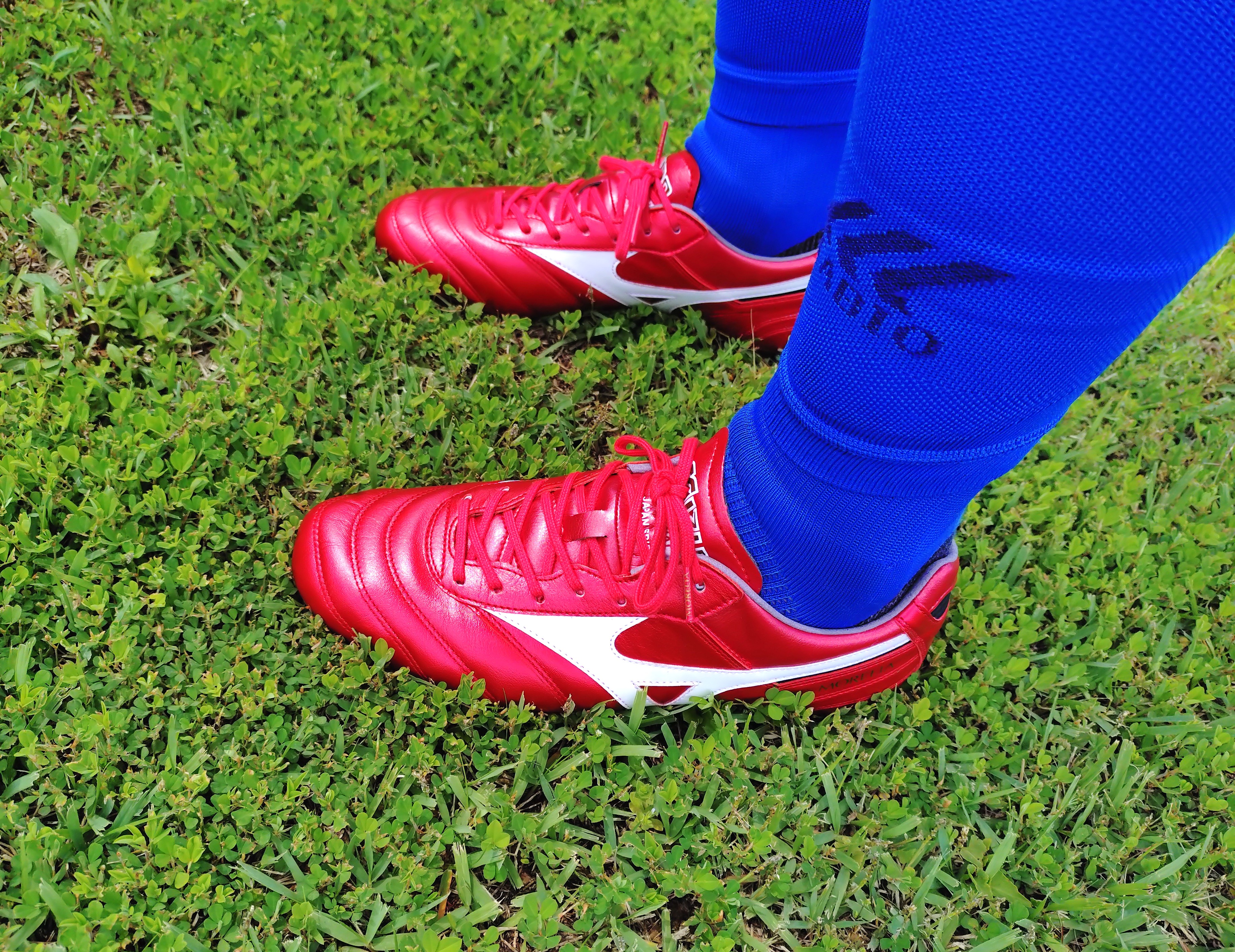Mizuno Morelia II cleats in red on green grass