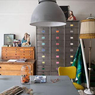 home office with white wall and grey desk and locker with pendant lamp and yellow chair