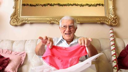 Photo of an older person holding up a pair of pink underpants from a gift